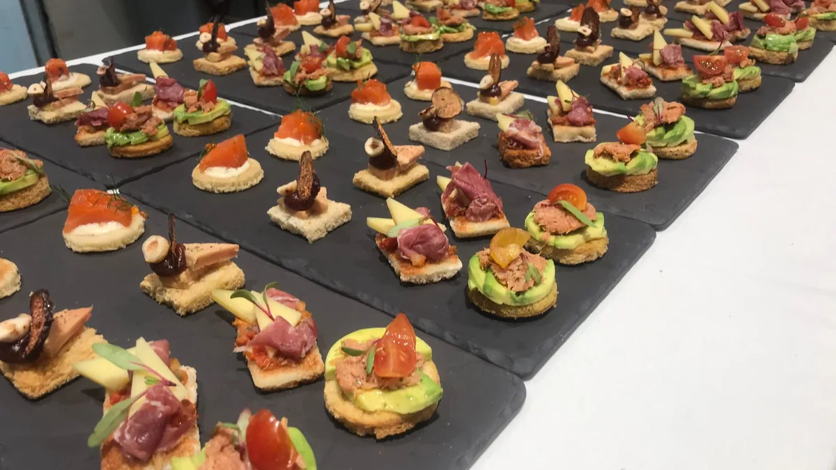 Montaje de canapés sobre pizarras de servicio en un evento corporativo