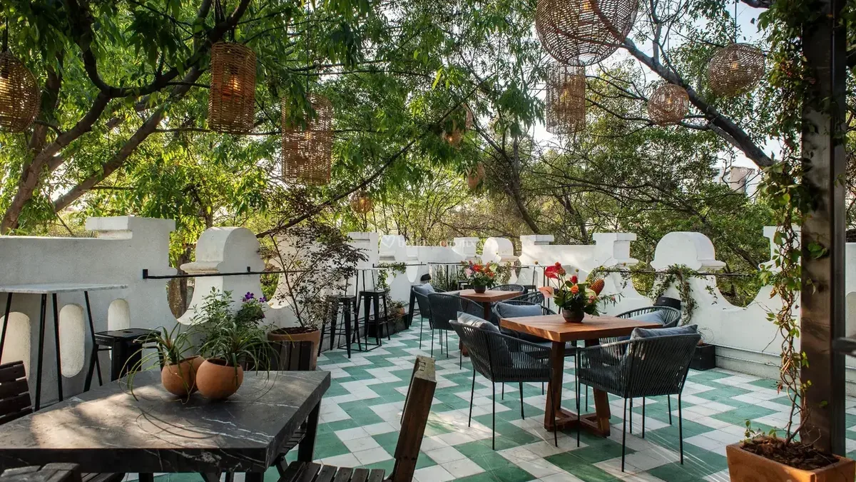 Terraza arbolada con mesas listas para el servicio